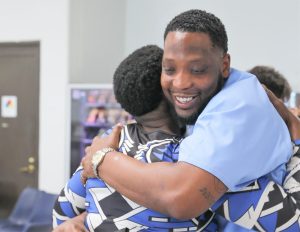 A CALPIA graduate hugs a family member after receiving certification at Centinela State Prison.