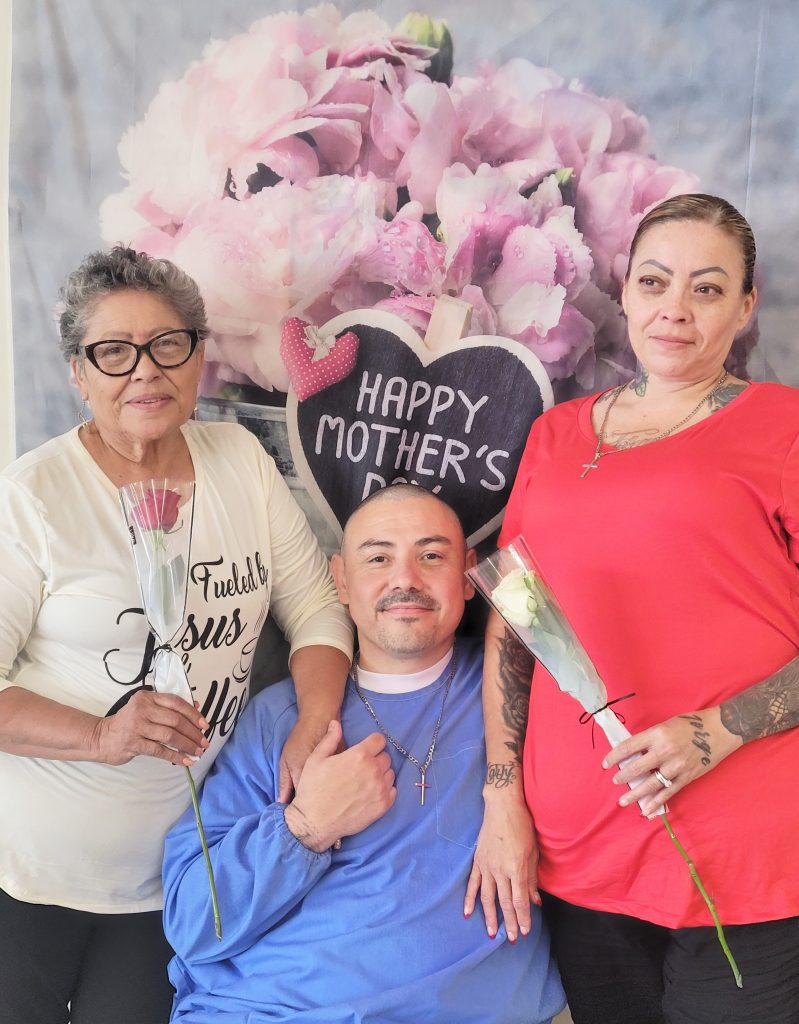 Two women holding flowers visit their incarcerated loved one on Mother's Day.