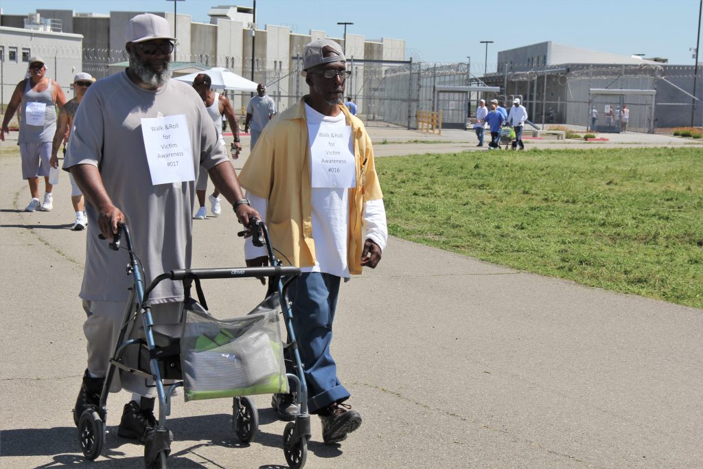 Incarcerated people walk around a track at a California prison.