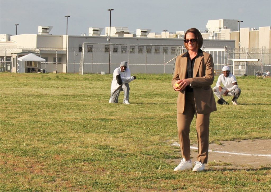 Prison warden throws first pitch at a softball game.