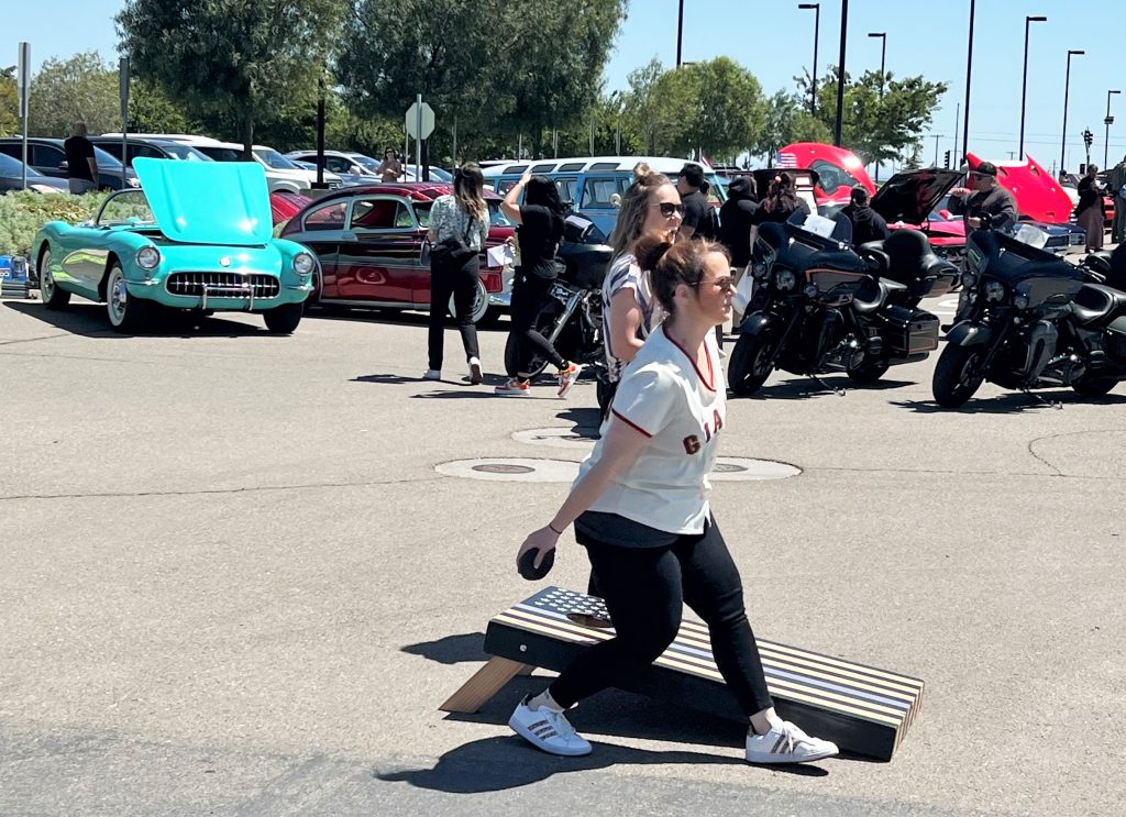 A female staff member prepares to toss a beanbag in a game of cornhole during an automotive show at CHCF.