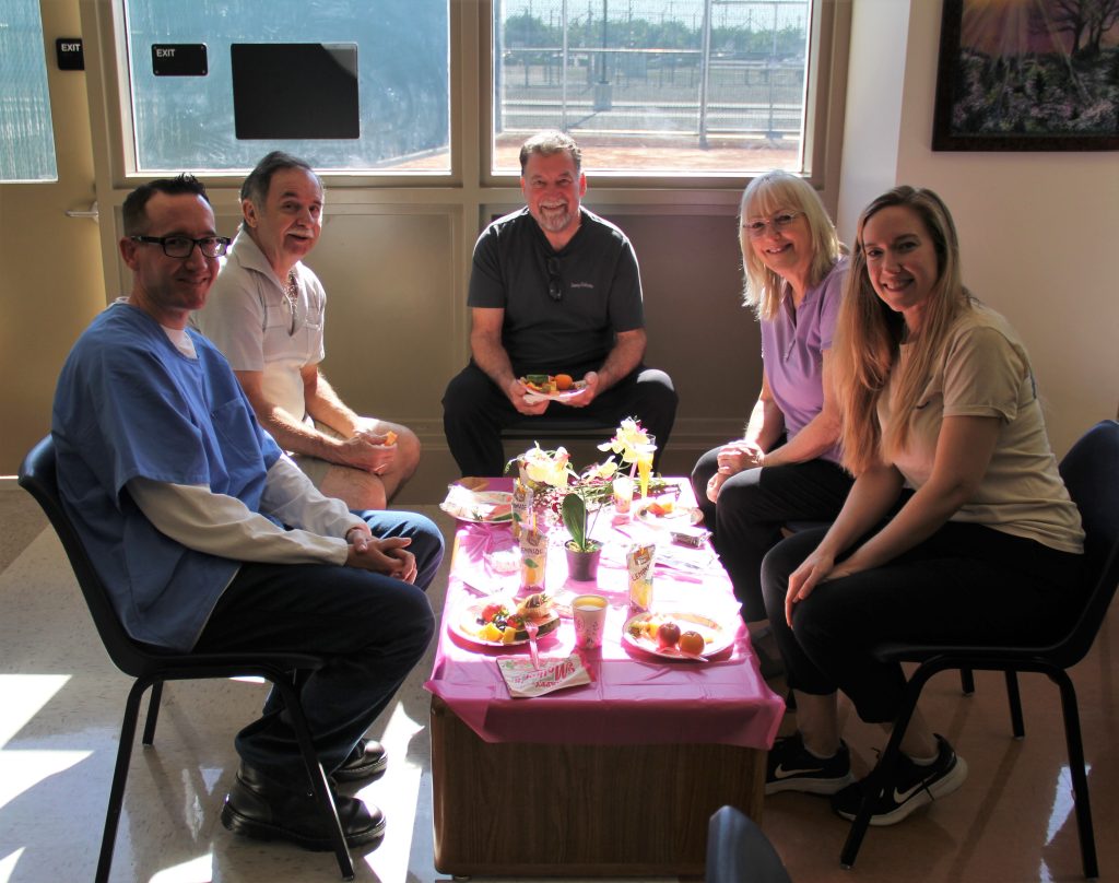 Family gathers around a table during CDCR Mother's Day visiting at California Health Care Facility in Stockton.