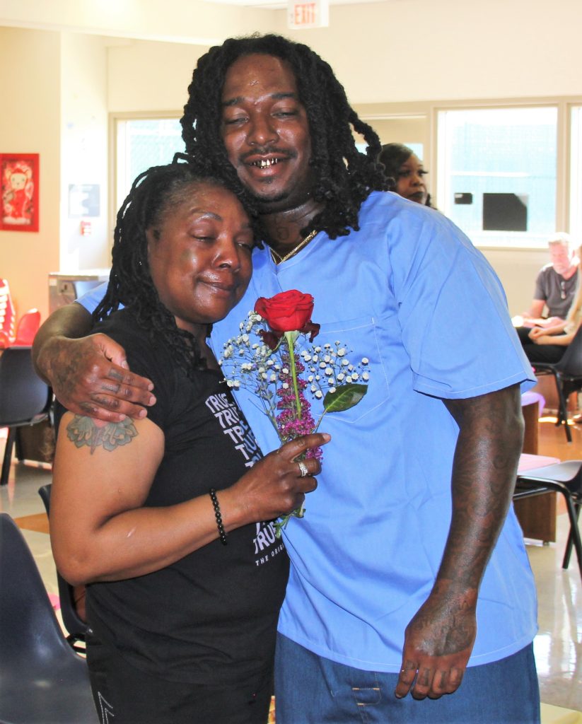 A woman holds a rose at a prison visiting event on Mother's Day.