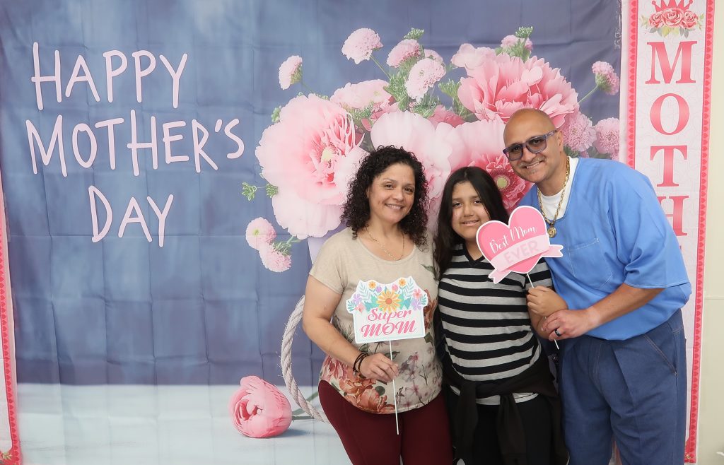 Mother's Day photo backdrop with an incarcerated person, a woman and a child.