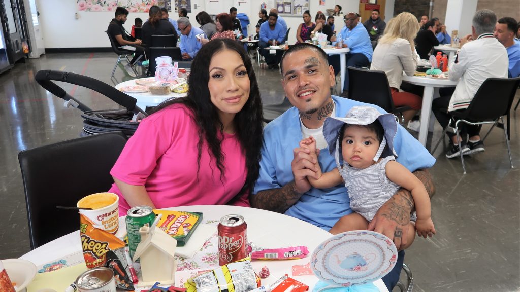 A baby and mother with their incarcerated loved one at California Men's Colony.