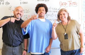 First GED earned by student a minimum support facility in Calipatria State Prison. He's shown with the principal and his instructor.