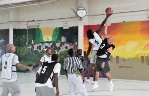 Intra-facility basketball game at Ironwood State Prison with players jumping for a ball.