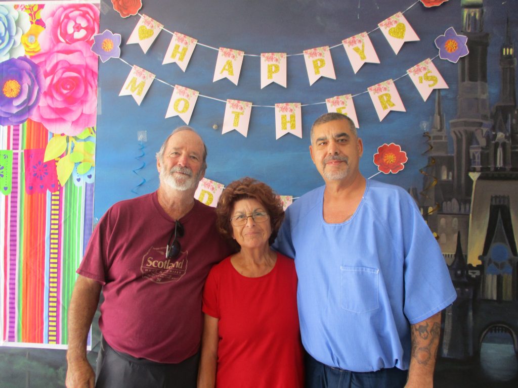 Two men, one of them incarcerated, and a woman during prison visiting.