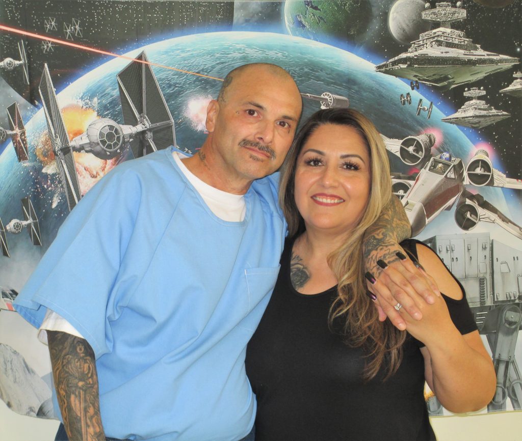 A couple pose for a photo with a spaceship themed backdrop. 