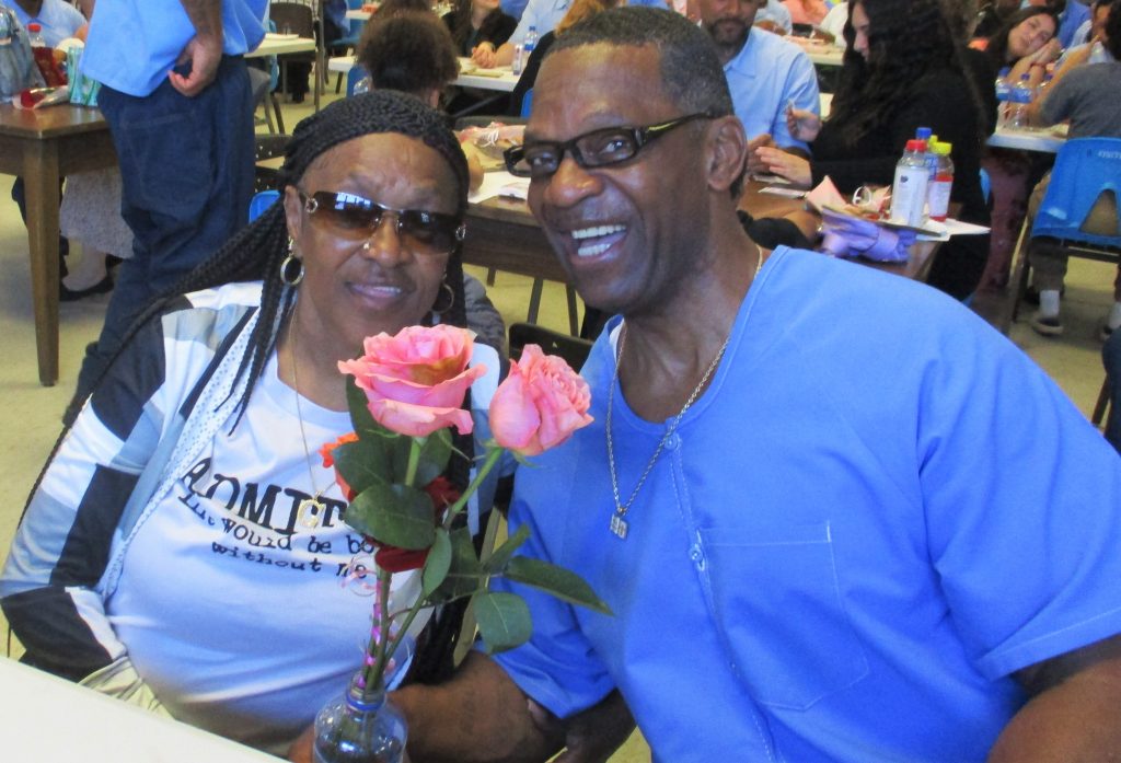 Incarcerated person and a woman holding two roses.
