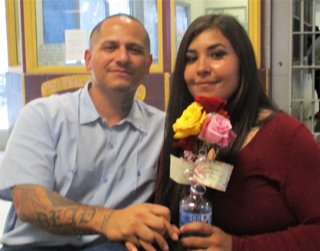 An incarcerated man and a woman holding flowers.
