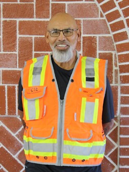 Anthony Salamanca wearing a safety vest with a brick wall behind him.