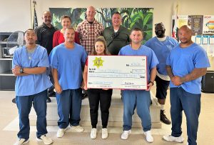 Wasco State Prison population with Special Olympics, an oversized check, and prison leadership.