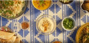 A table showing soups and salads along with a bowl of hummus in the center.