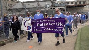 Folsom State Prison incarcerated people walking while holding a Relay for Life banner.