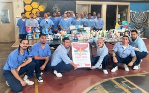 Avenal State Prison YOP participants with a table full of personal hygiene items they collected to benefit people in need in the community.