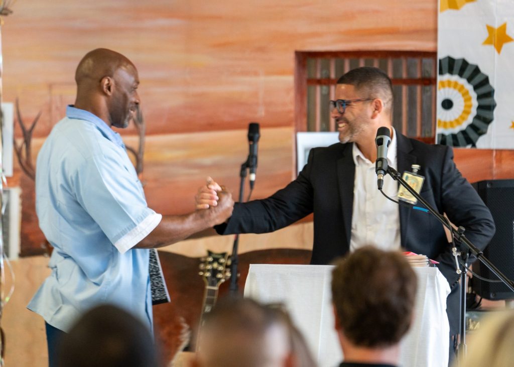 Two people at a graduation event inside a prison.