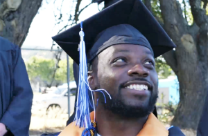 College graduate smiling as he attends graduation ceremony on campus.