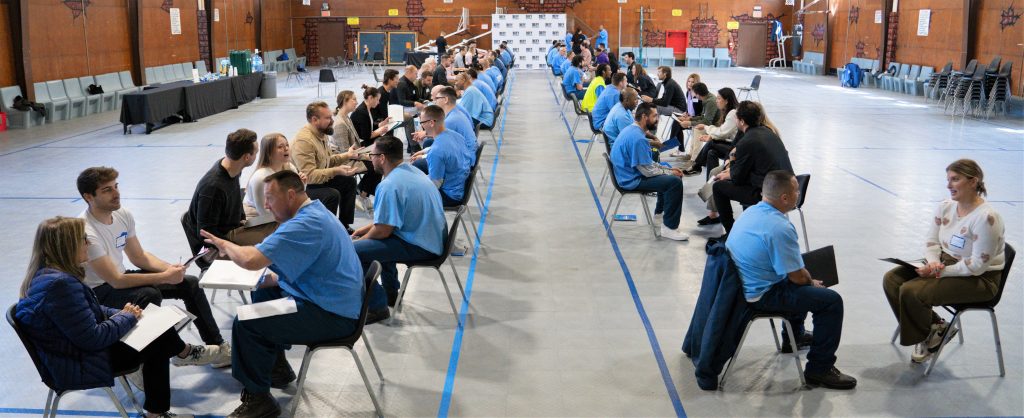 A group of incarcerated people speak with business coaches from Defy Ventures at CRC.