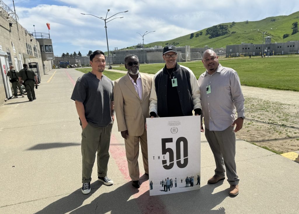 Four people with a sign that says "The 50."