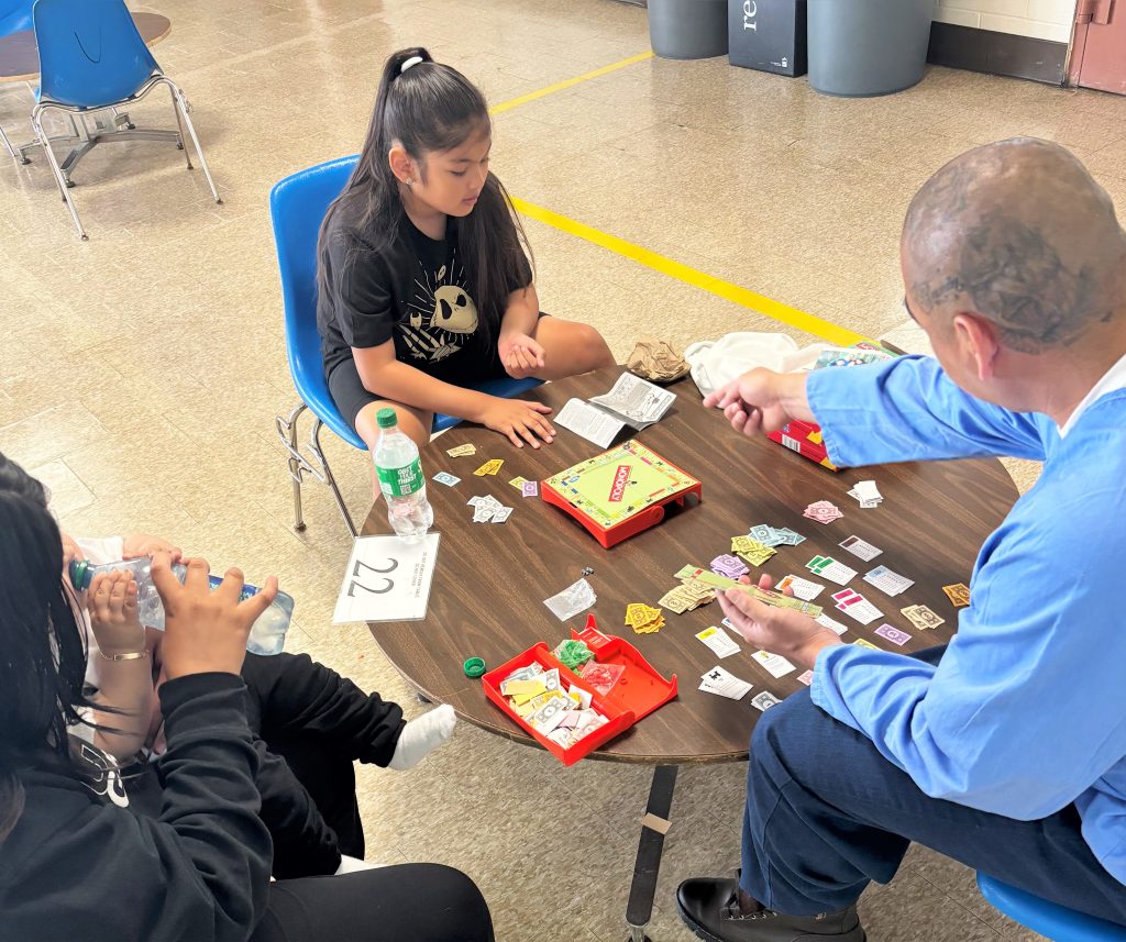 Father's Day visiting at Pelican Bay State Prison with a mom, baby, young child and an incarcerated man seated around a table. 