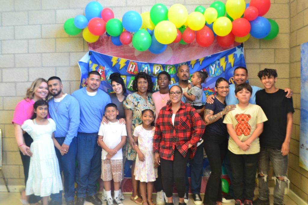 Families and incarcerated people pose for a group photo.
