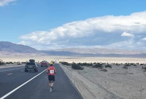 Running across the desert with clouds and mountains in the background.