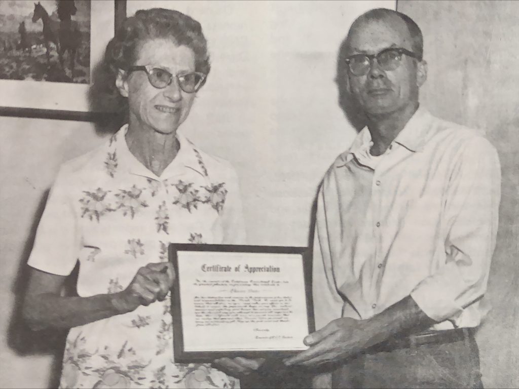 An incarcerated person presents a certificate of appreciation to Eleanor Dieter.