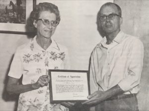 An incarcerated person presents a certificate of appreciation to Eleanor Dieter.