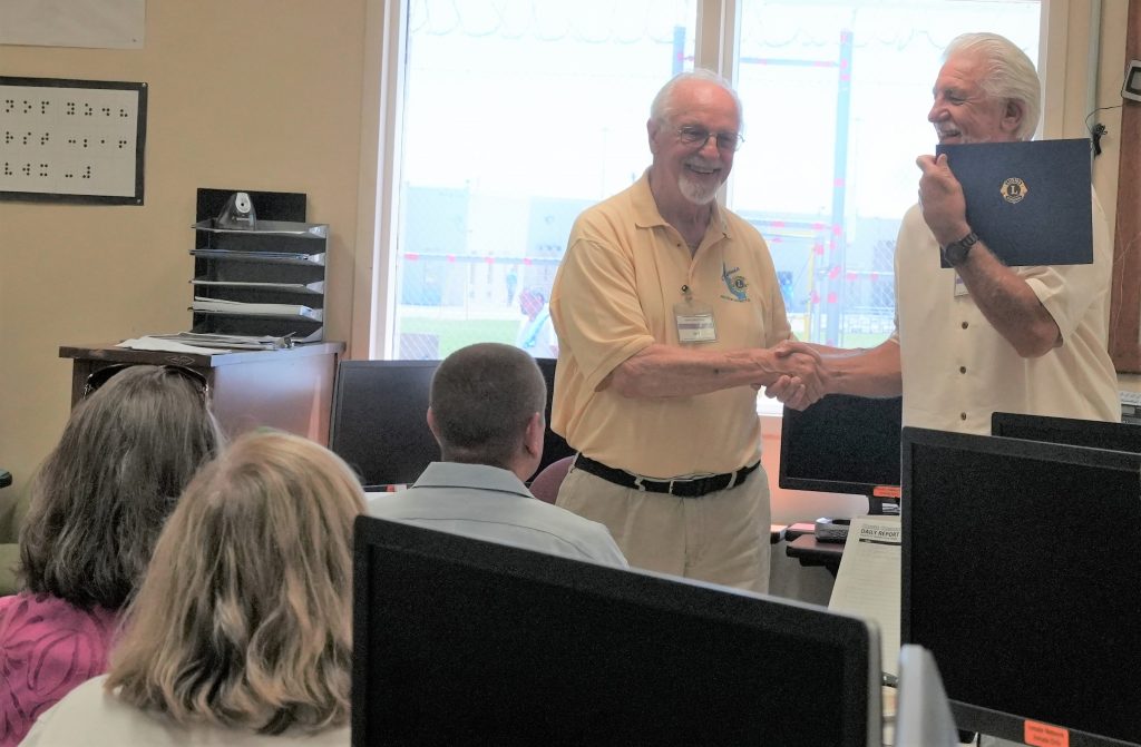 Two Lions Club members shake hands at Avenal State Prison.