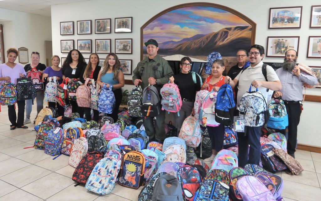 Calipatria State Prison school drive with staff holding donated backpacks.