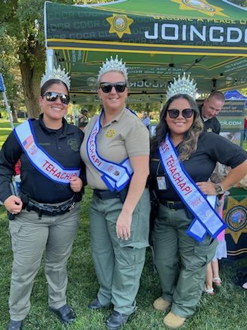 Three CDCR staff wearing tiaras and sashes.