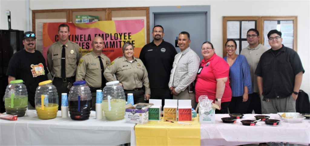 Centinela employees activities committee members stand behind a table for a salsa contest.