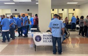 A certified mentor stands beside the Board of Parole Hearings table.