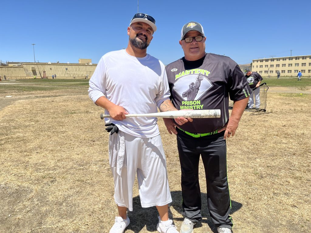 Two men, one of them incarcerated, hold a baseball bat at California Men's Colony.