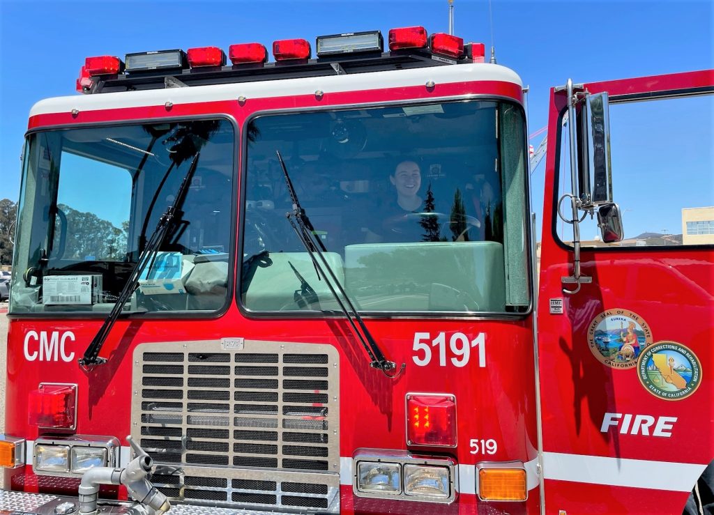 A woman sits in the driver's seat of a fire engine during family day.