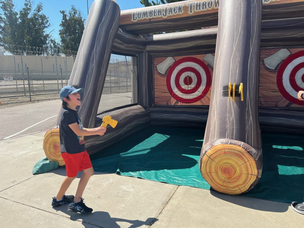 A child holds a plastic ax as he prepares to throw at a target.