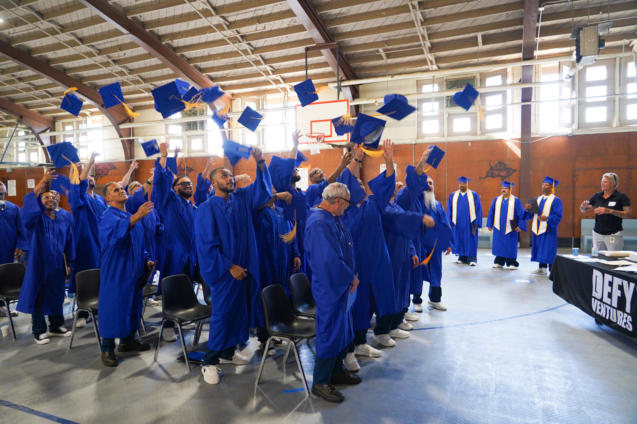 Defy Ventures graduates toss their hats in the air at California Rehabilitation Center, more commonly known as CRC.