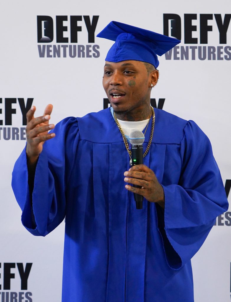 Business pitch and Defy Ventures graduation at CRC with a person speaking into a microphone.