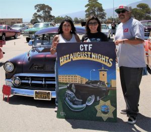 CTF staff holding Hot August Nights poster at car show