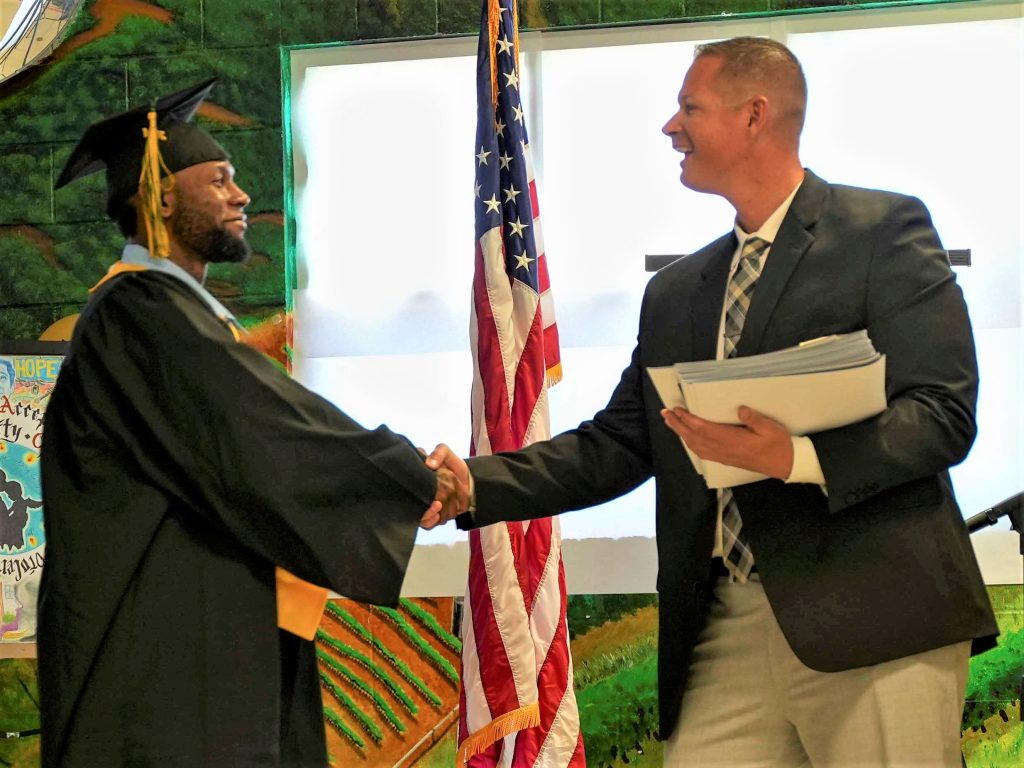 graduate shakes hands with SOL staff at OMCP graduation