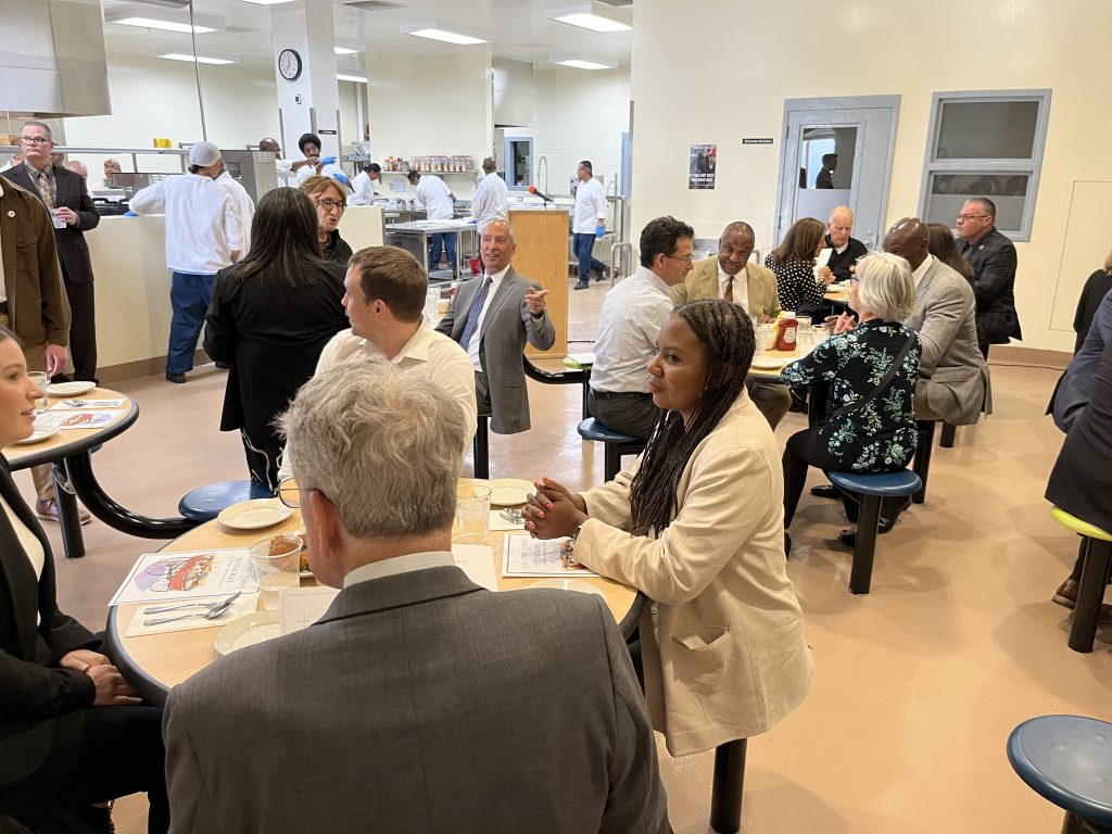 Restaurant with variety of people sitting at tables eating a meal.