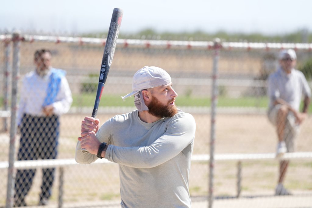 Man holds a baseball bat during a softball game at a Valley State Prison Olympic-style event.
