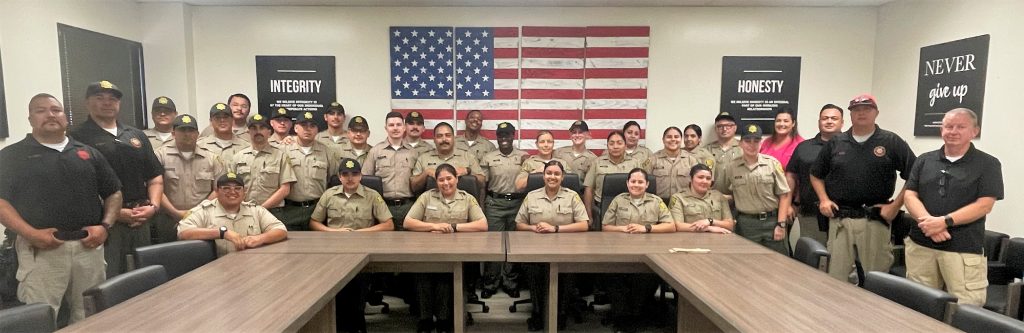 Cadets sitting at a table with the American flag behind them.