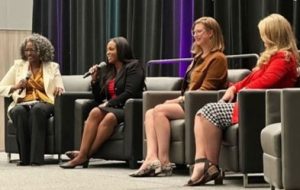 Women's conference with a panel of speakers, including associate warden Delinia Lewis.