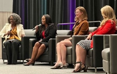Women's conference with a panel of speakers, including associate warden Delinia Lewis.