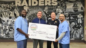 CTF warden, police chief, two incarcerated people, and an oversized check.