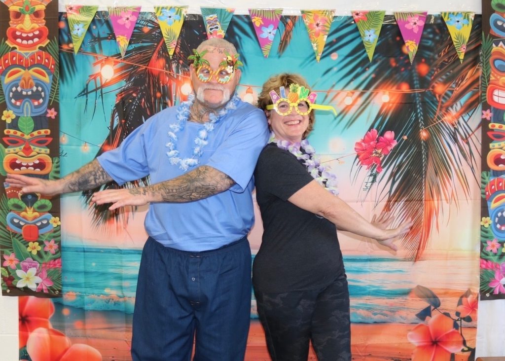 An incarcerated person and his visitor pose in front of a backdrop at Mule Creek State Prison.