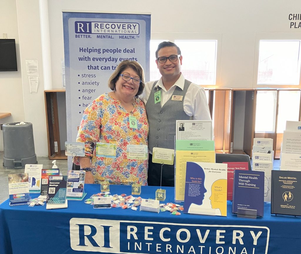 Recovery International booth with two people standing behind the table.