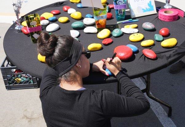 A staff member paints rocks.